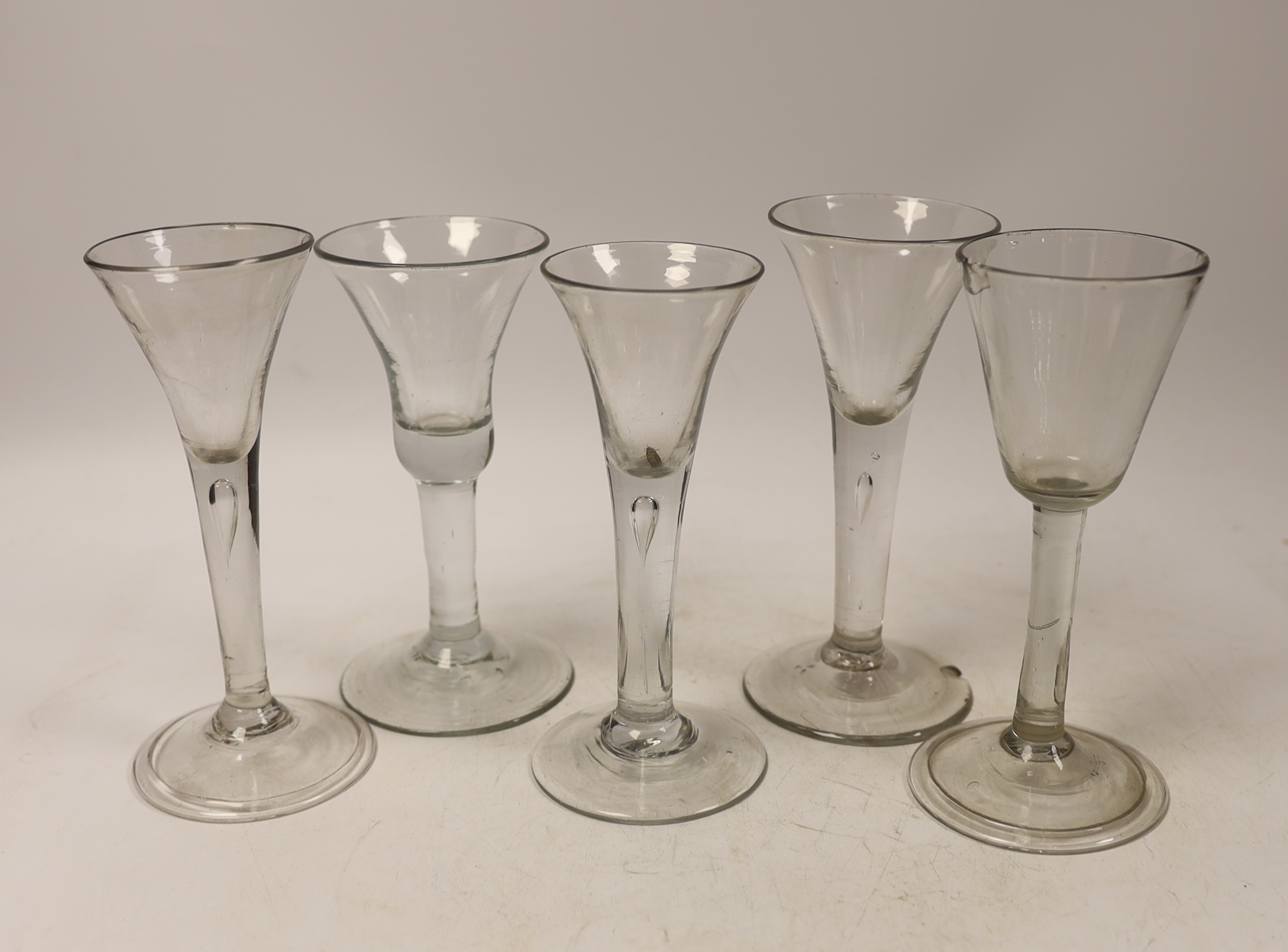 Five mid-18th century plain stem wine glasses, including three with drawn trumpet shaped bowls, two examples with folded feet, tallest 16cm